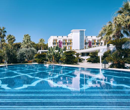 Luxury hotel with panoramic swimming pool, surrounded by tropical greenery, with elegant white architecture and an exclusive atmosphere.