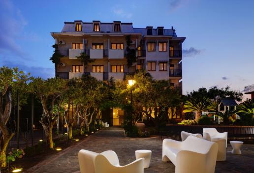 Hôtel élégant au coucher du soleil, avec jardin éclairé et espace détente extérieur.