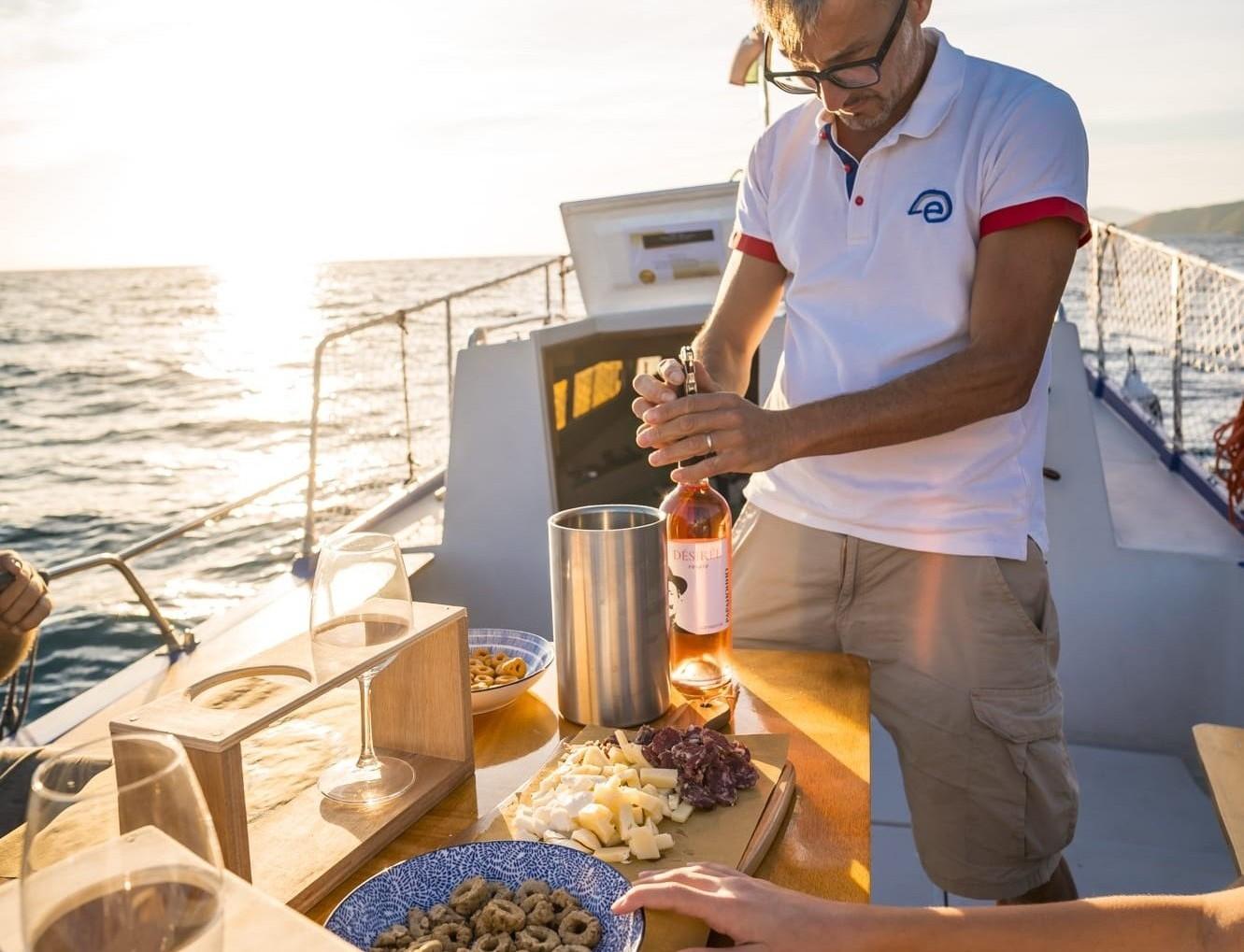 Wine and typical product tasting on board a boat at sunset on the sea.