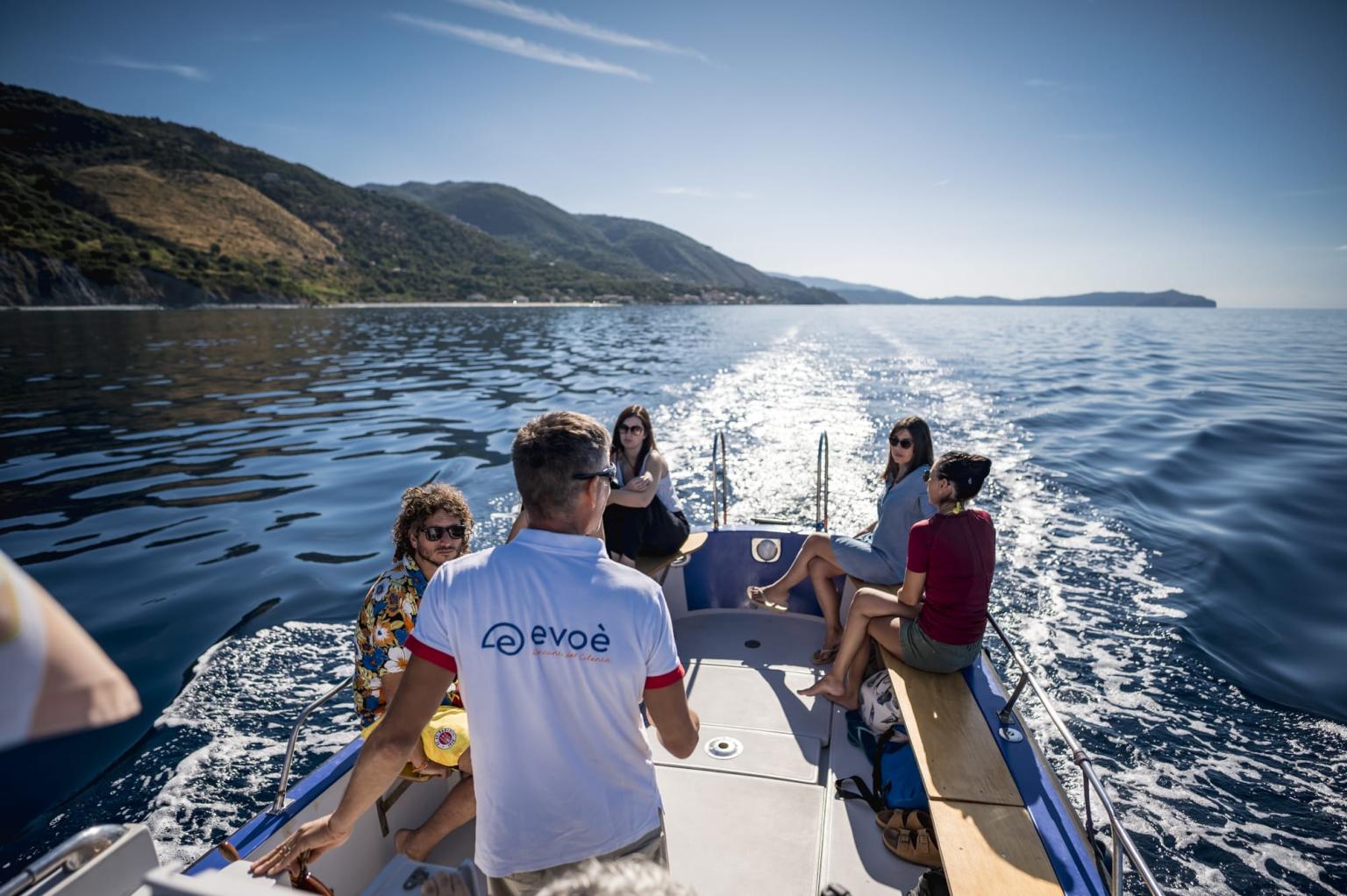 Bootsfahrt entlang der Panoramaküste mit Touristen an Bord und kristallklarem, von der Sonne beleuchtetem Meer.