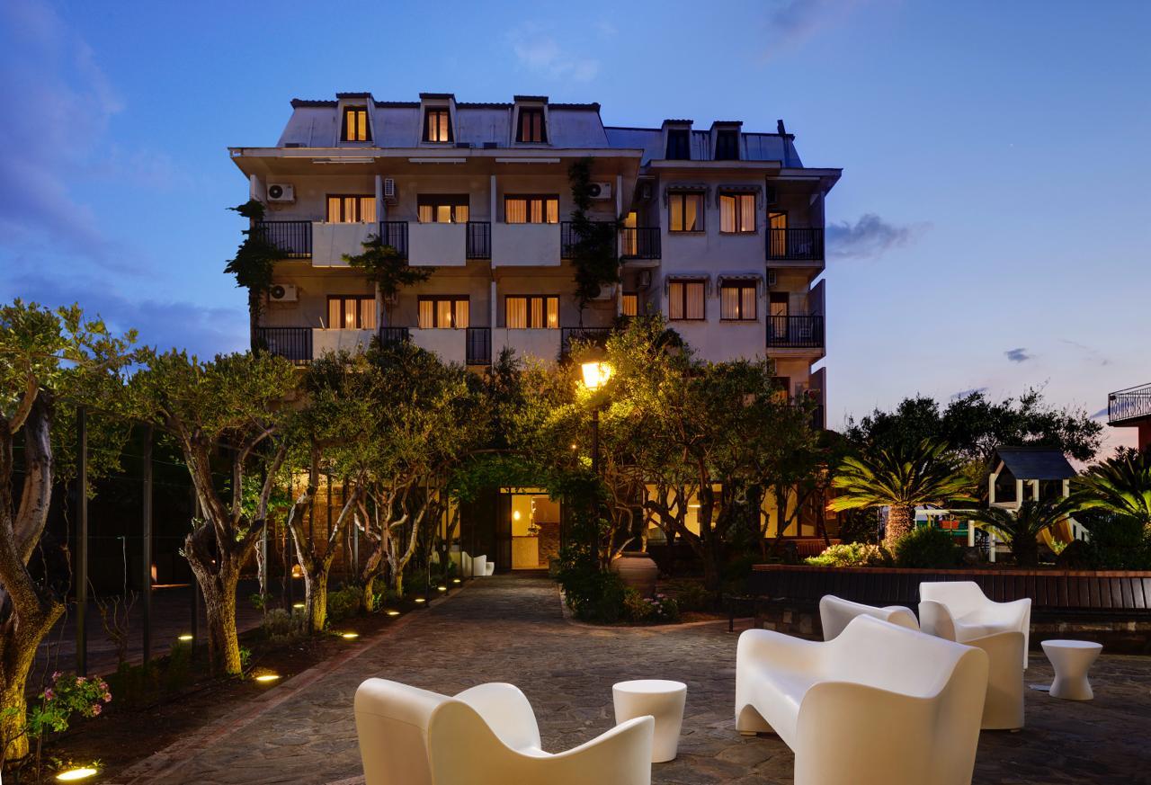 Hôtel élégant au coucher du soleil, avec jardin éclairé et espace détente extérieur.