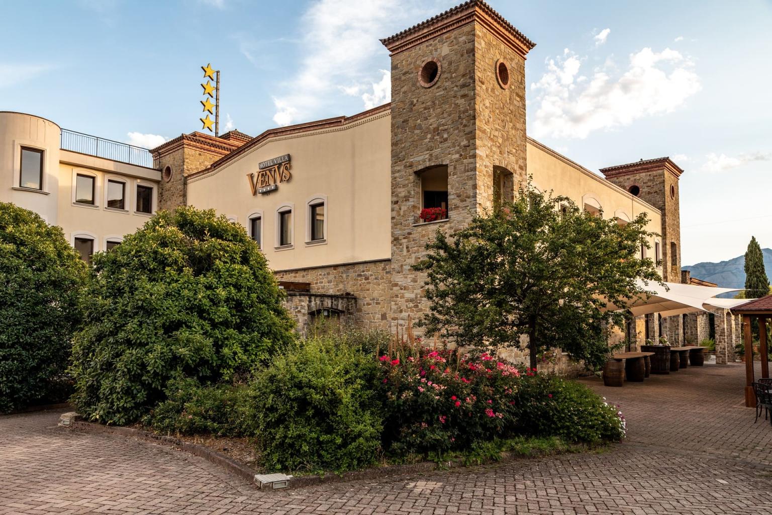 Elegant stone structure surrounded by greenery with a flowered garden and mountain views.