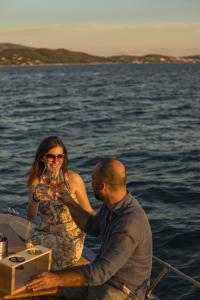 A couple toasts with glasses of wine on a boat at sunset, surrounded by a romantic seascape.
