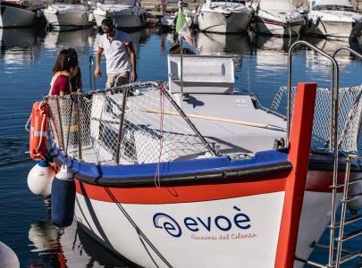 Evoè tour boat in the harbor, with a white and red hull.