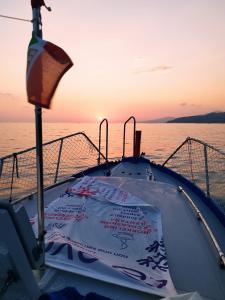 Boat at sea at sunset, with a view of the sun sinking below the horizon.