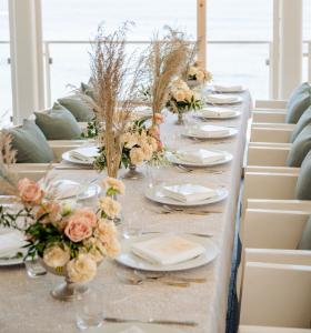 Elegant table setting with a floral centerpiece and panoramic sea view.