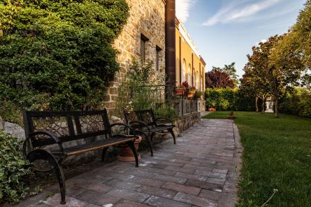 Elegant, well-maintained garden with benches, a stone pathway, and a historic masonry façade, surrounded by greenery.