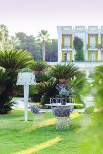 Elegant garden with a white wrought-iron table and chairs, palm trees and lush vegetation.