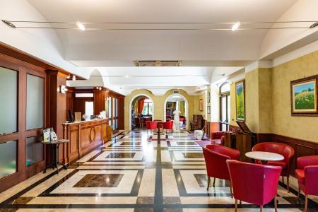 Elegant reception with classic furnishings, marble flooring and lounge area with red armchairs.