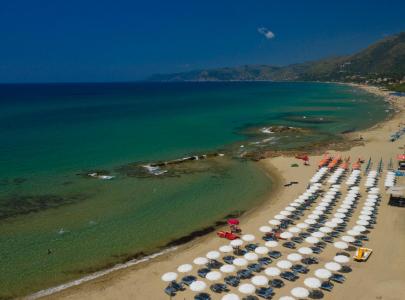 Plage de sable doré avec des parasols blancs et une mer turquoise aux eaux cristallines.