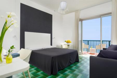 Chambre moderne et lumineuse avec un lit double, un mobilier élégant, une grande baie vitrée et une vue sur la mer.