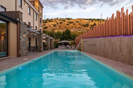 Hotel outdoor swimming pool, surrounded by a relaxation area, sun loungers, and views of the surrounding nature.